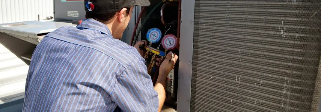 HVAC technician servicing a condenser unit in Crowley